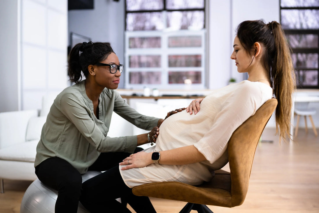 A Doula or Midwife sits with a pregnant woman