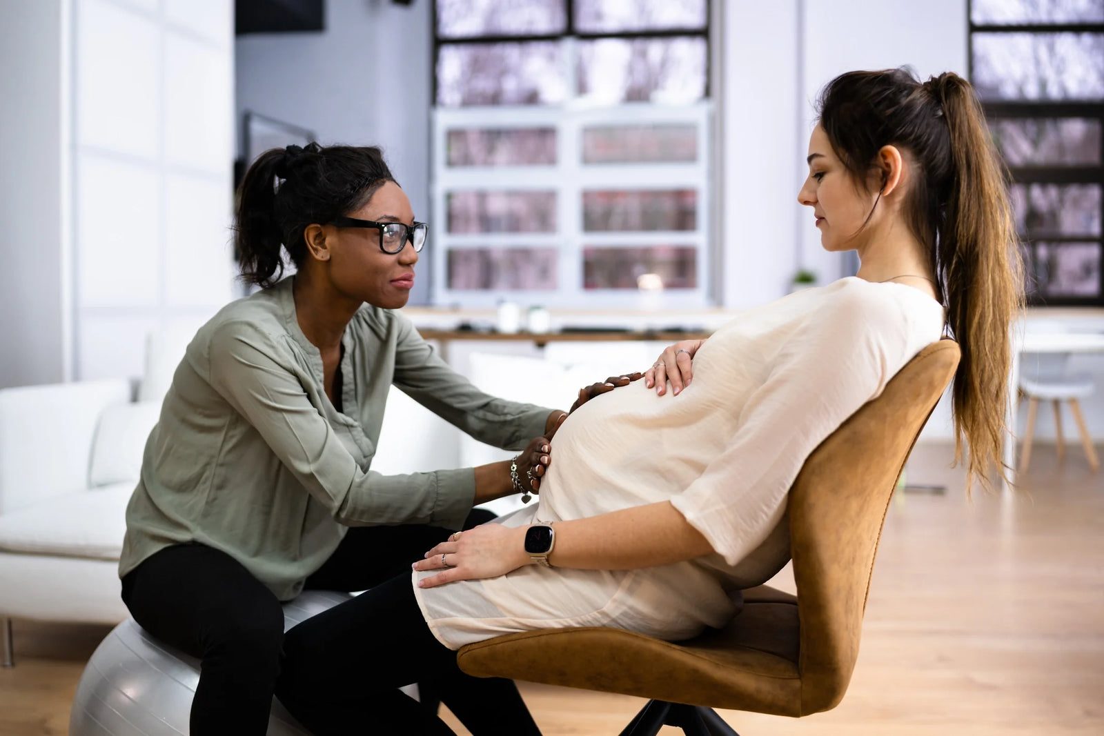 A Doula or Midwife sits with a pregnant woman