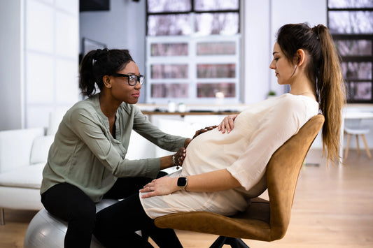 A Doula or Midwife sits with a pregnant woman