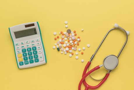 A calculator, medication, and a stethoscope on a yellow background