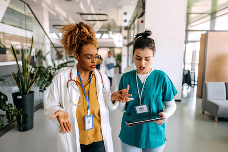 Two young female nurses consult with eachother in the hospital