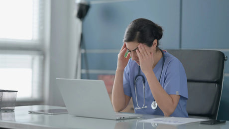 A young female woman nursing student massages her temples as she studies for the NCLEX