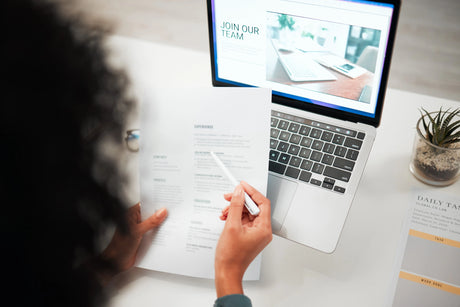 Nurse looking at nursing resume in front of computer