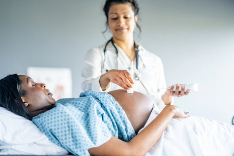 Nurse using electric fetal heart rate monitor on pregnant woman in hospital