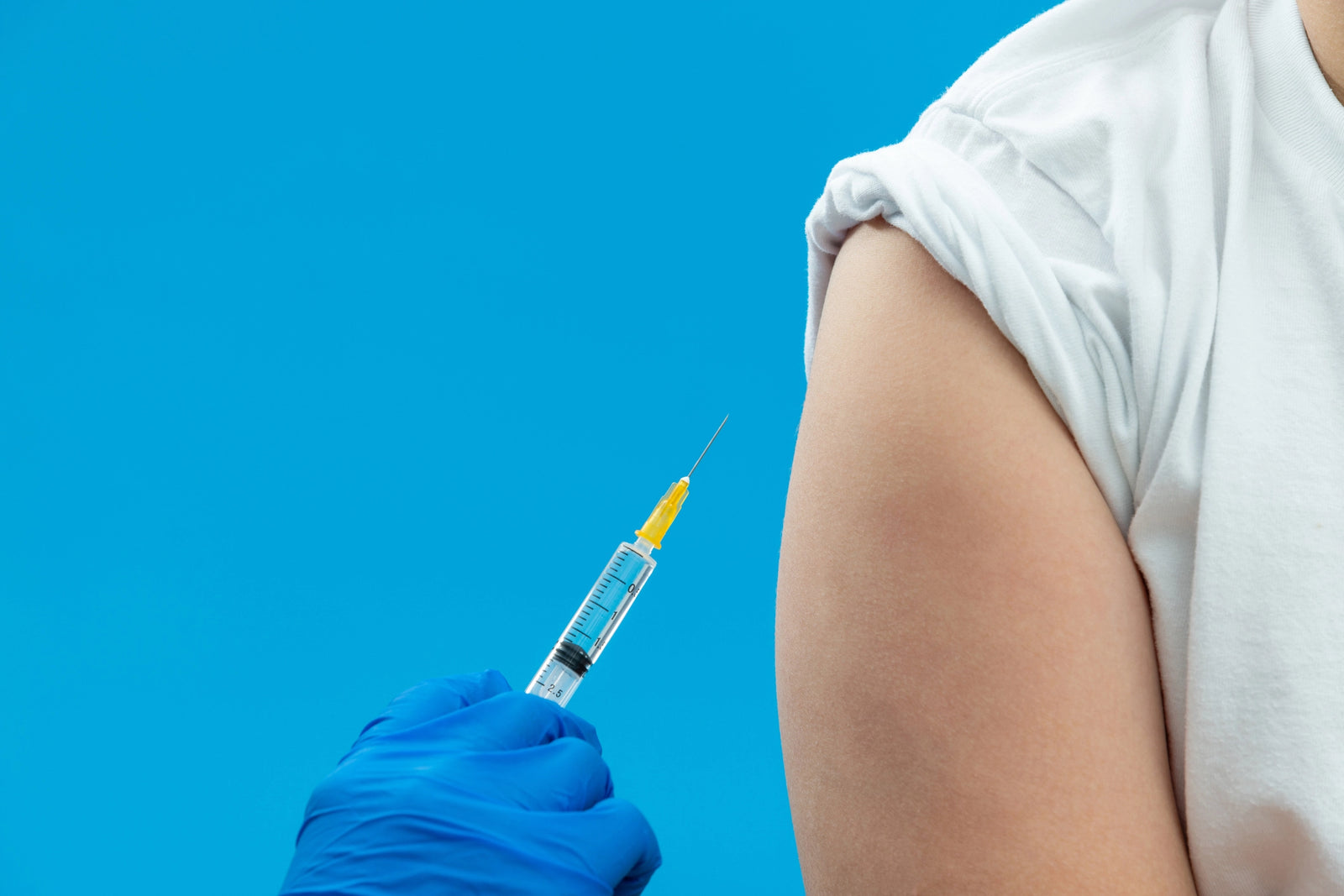 Nurse with blue latex gloves preps an upper arm for a subcutaneous injection