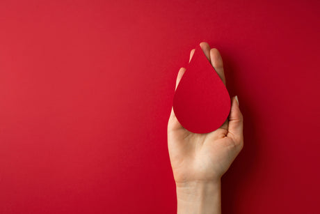 Red drop of blood on a nurses hand with a red background