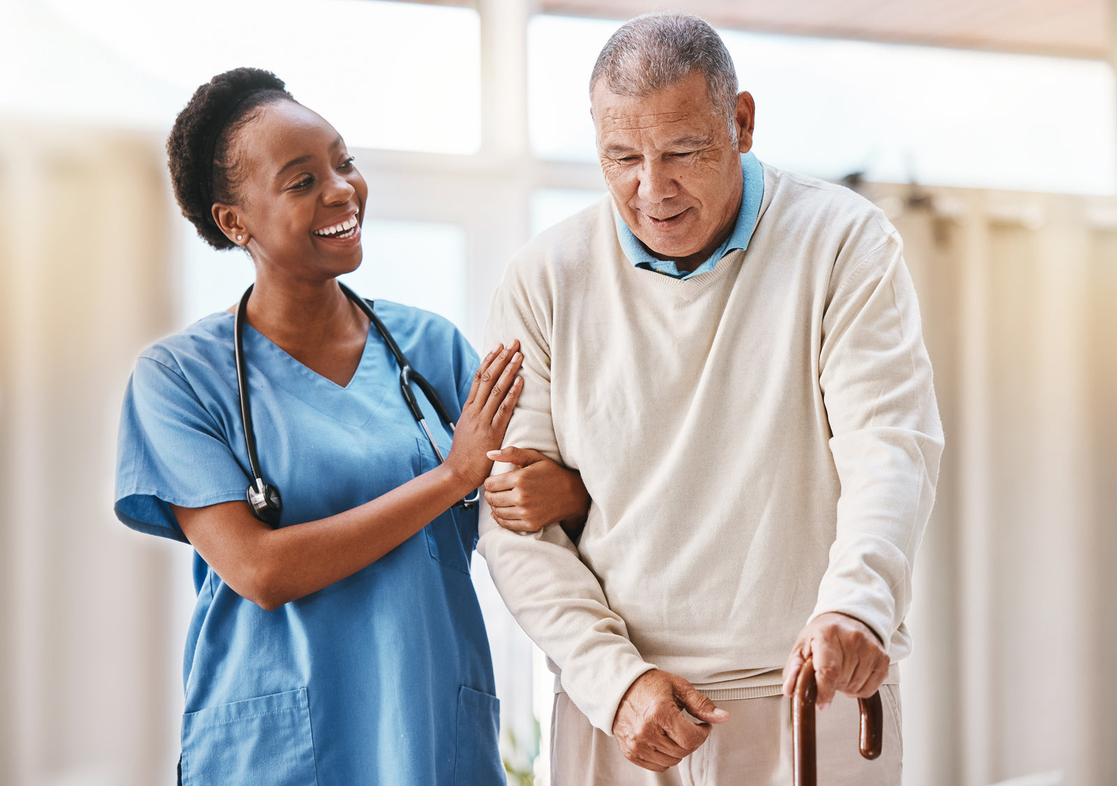 Young Black female nurse aids an older man who is at risk for falls.