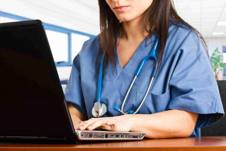 Brunet female nurse in blue scrubs studies for the nursing exam on her laptop best teas test study guide