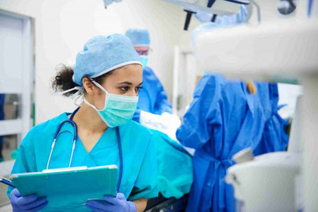 Preoperative female nurse with clipboard and full PPE and scrubs What Is Perioperative Nursing