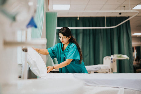 Young female nurse in green scrubs makes a hospital bed how much nurses make