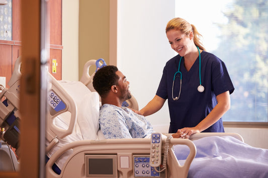 Smiling female nurse reassures young African American patient lying in a hospital bed positioning guide
