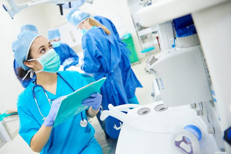 Surgical nurse in PPE and scrubs in a surgical theater during surgery surgical nurse working