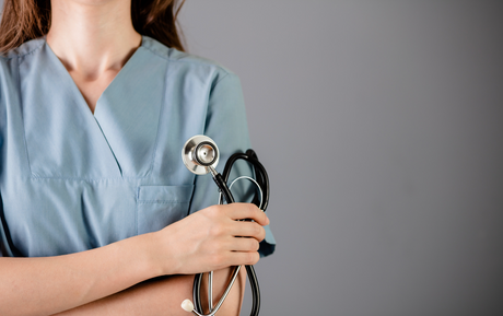 Young woman female nurse in scrubs holds a stethoscope