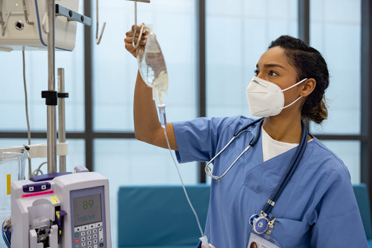 Young woman female nurse checks the IV line in a hospital room ICU recovery room.