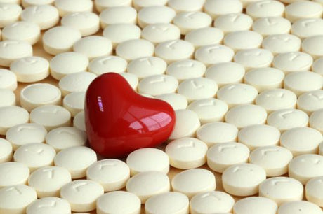 A ceramic red heart on a field of white pills