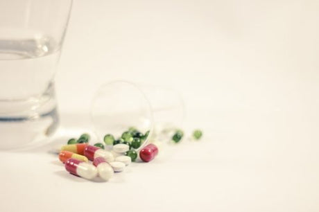 Assorted capsules and meds and a glass of water