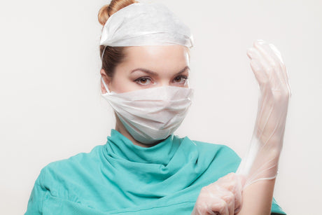 A pretty female Nursing student in scrubs, a mask, a hairnet, and gloves