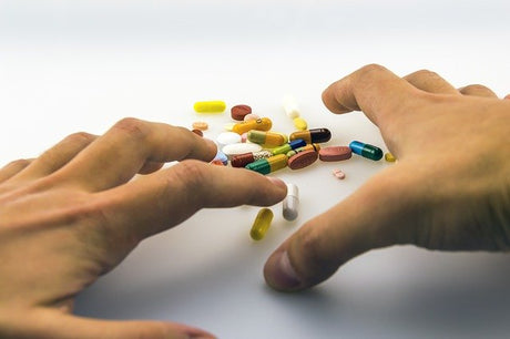 Hands grasping at pills and capsules