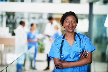 Portrait of a black woman healthcare worker standing in a hospital with colleagues in the background