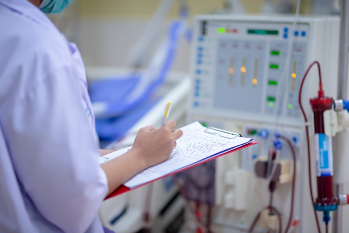 Nurse with clipboard next to dialysis machine - nursing interventions for acute renal failure title card