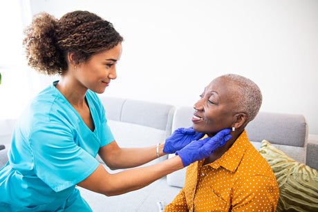 Pretty young African American nurse checking hodgkin vs non hodgkin lymphoma on middle aged female African American patient