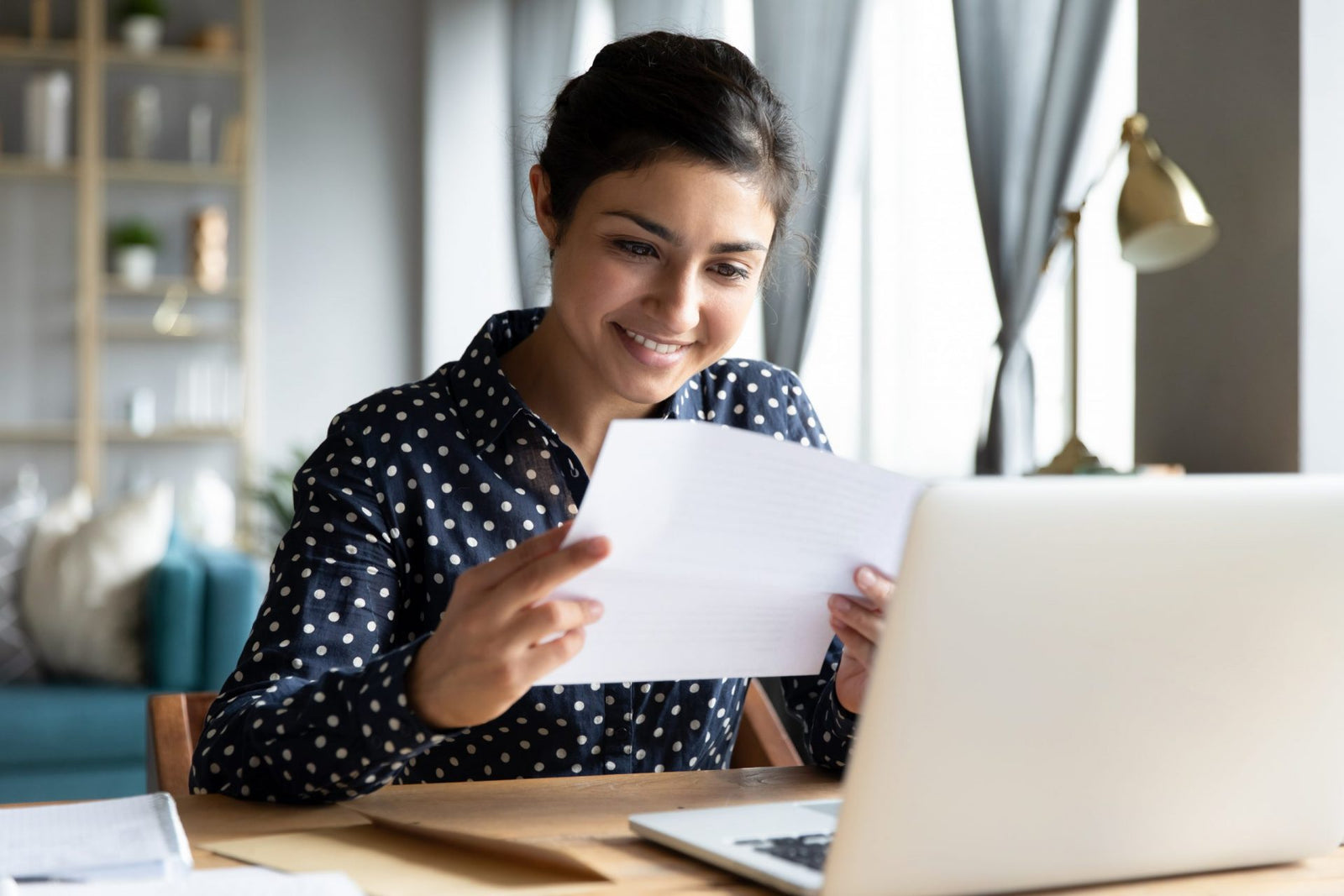 Smiling young woman holding paper scholarship grant for nursing school