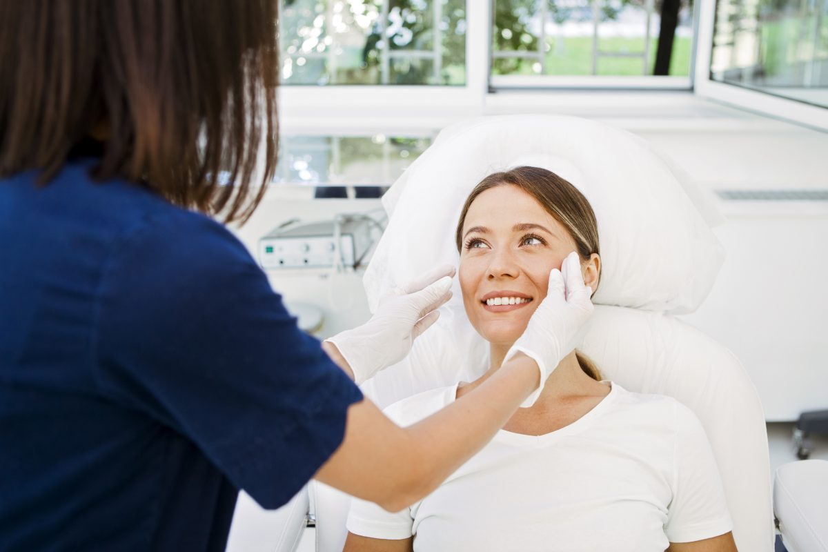 Nurse assessing for Chvostek’s sign in a young woman patient.