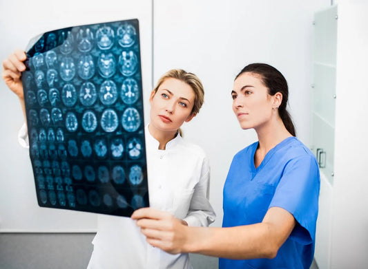 Experienced woman nurse practitioner and radiology nurse are looking at an MRI scan of a patient's head. Diagnostics and treatment of brain diseases, headaches, tumors and brain cancer.