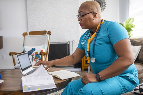 A black female nurse studying for another degree studies between her shifts