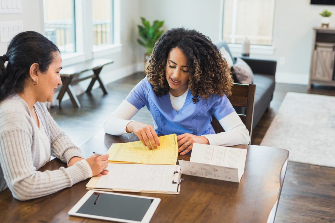 A serious female home healthcare nurse reviews medical documents with a mature female patient.