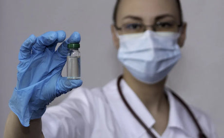 Nurse in a PPE mask holds a vial with her PPE gloved hand. Cholinergic vs Anticholinergic Pharmacology Made Easy