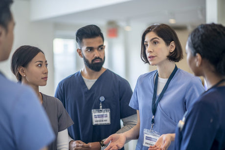 Pretty young brunette nurse talks to her fellow nursing students in a hospital