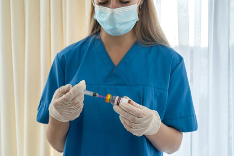 a young experienced nurse with blond hair in a mask and gloves is dialing a vaccine for a patient. Medicine concept. Vaccination concept