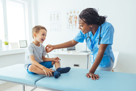 Happy psychology nurse and little boy smiling at each other in a medical office examination room.