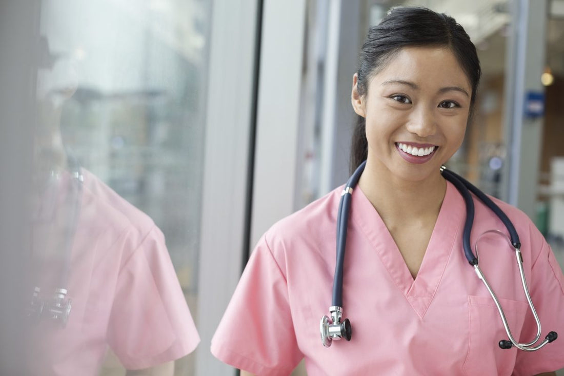 Portrait of smiling young Asian female nurse in pink scrubs