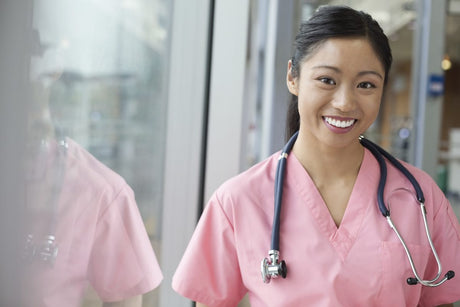 Portrait of smiling young Asian female nurse in pink scrubs