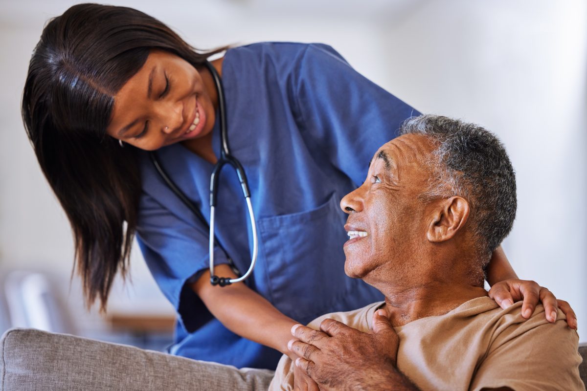 Beautiful African American Black nurse in hospice vs palliative care with a senior black man patient.