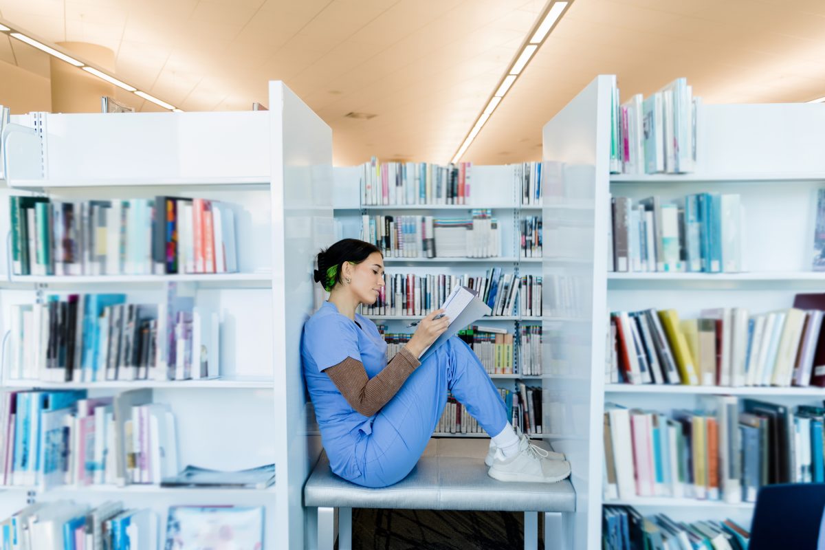 A young adult female medical student finds a quiet spot in the university library to study for her upcoming test.