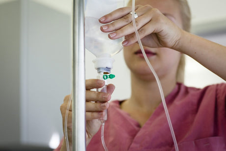 Medical nurse assistant is preparing an infusion. Nurse in hospital placing a bag of medicine on the line.