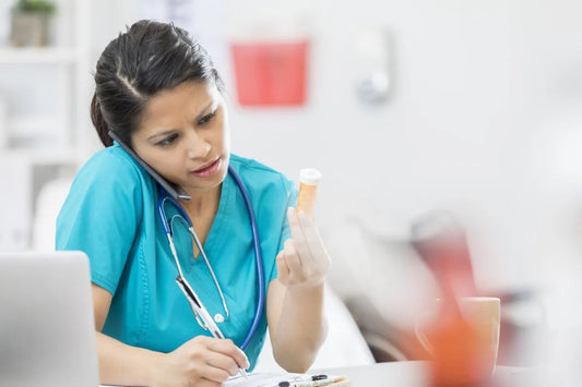 Confident nurse talks on a smart phone while reading a patient's prescription medication.