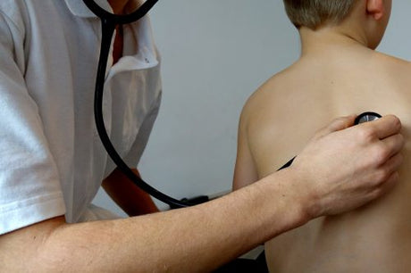 Make nurse checks the lungs of a boy with the stethoscope