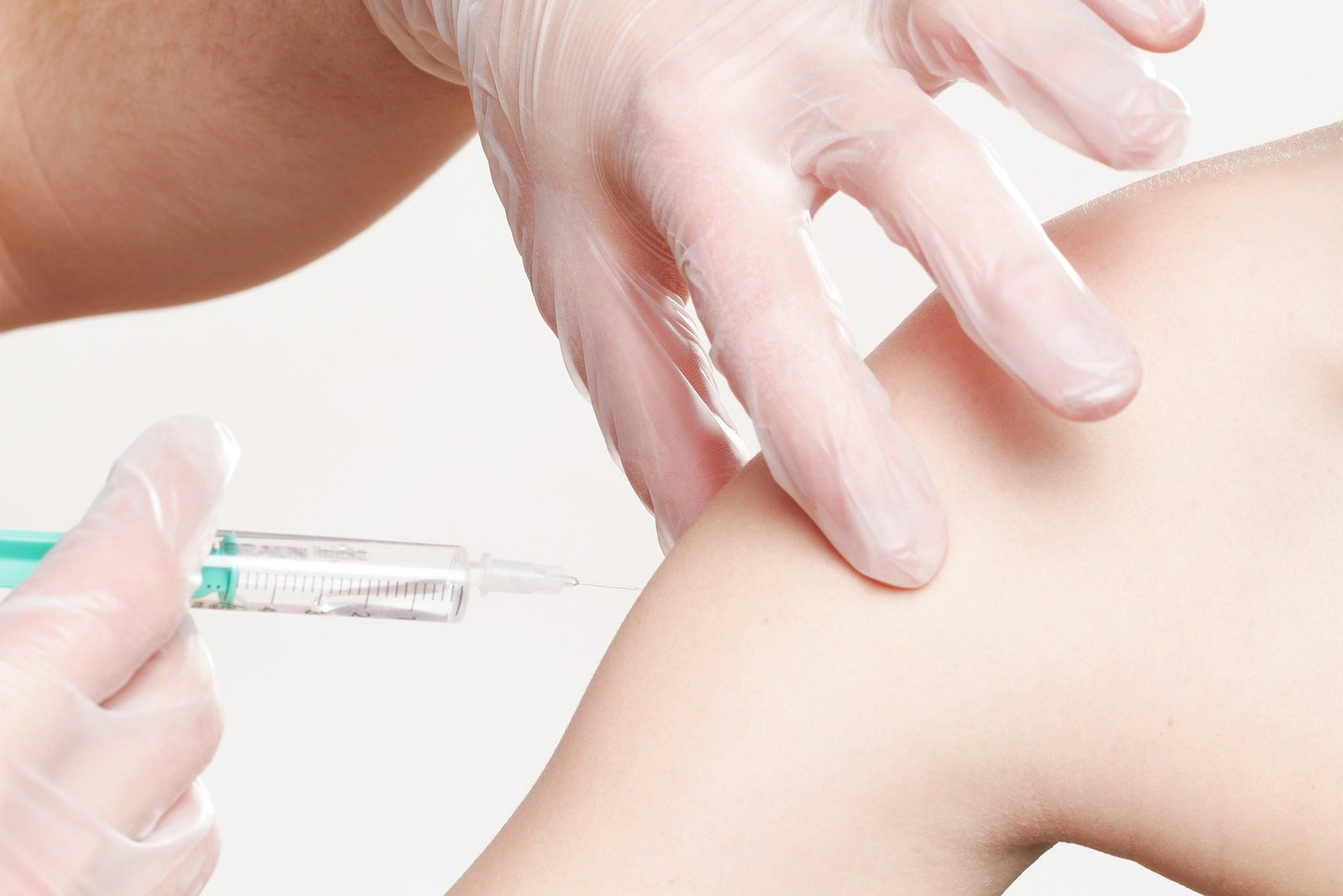 A nurse gives a vaccination to a patient's bare arm